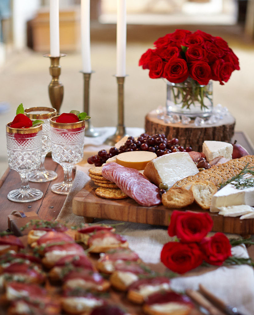 A party table set with roses and candles and cocktails