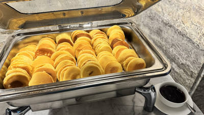 Stainless chafing dish on a buffet holding rows of small pancakes