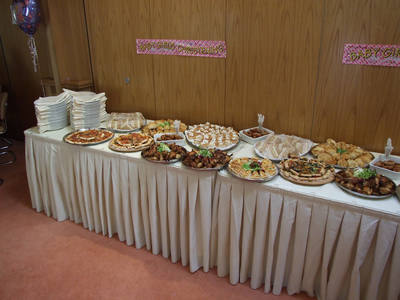 A long party buffet table lined with platters of finger food