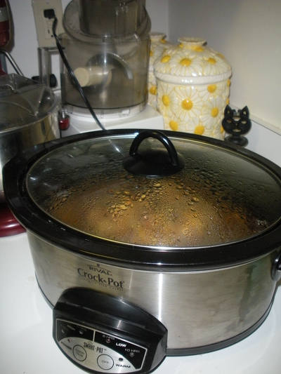 Stainless slow cooker with a glass lid on a kitchen counter